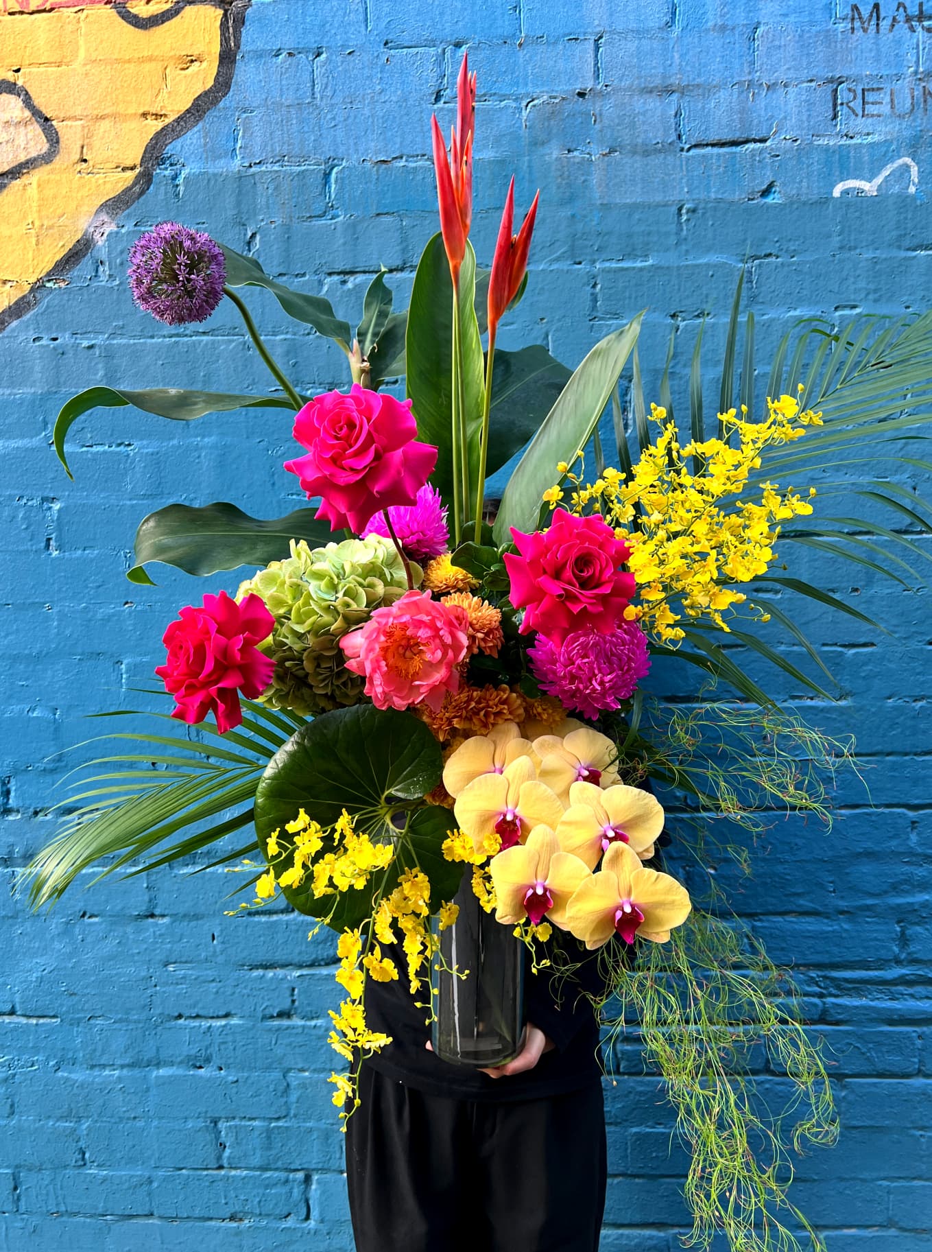 A vivid hand-tied arrangement of roses, orchids and natives